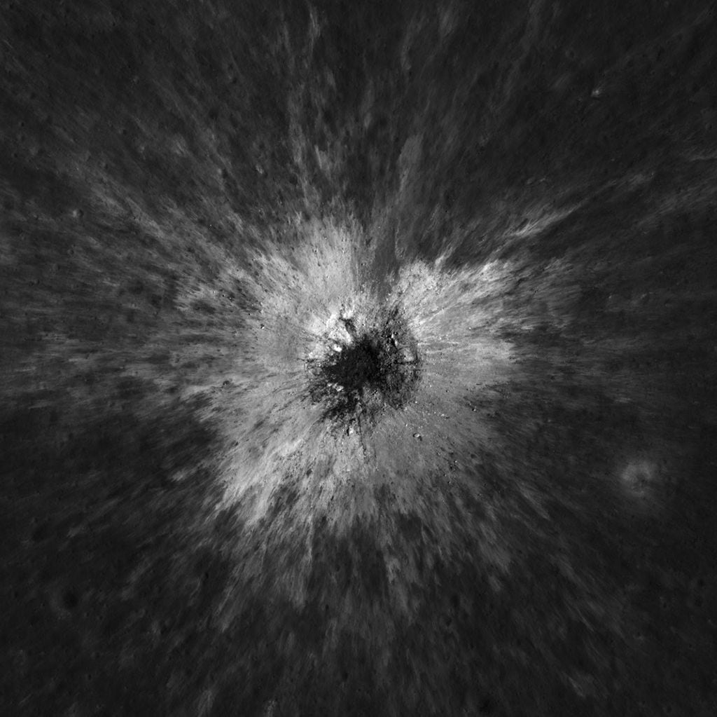 default-985 An overhead view shows a crater on the moon with bright ejecta surrounding it.